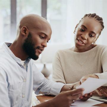 A young couple looking at statements and developing a savings strategy